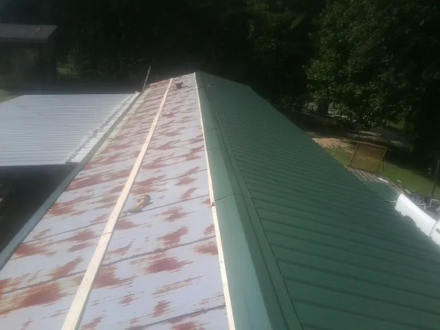 Old rusted panels beside newly installed green metal roofing — Wind Damage Roof Repair by Roofing Brothers in Moyie Springs