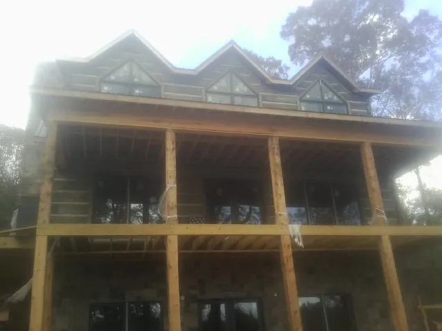 Dormers and porch framing on a large log home under construction — Roof Coating work by our crew in Moyie Springs