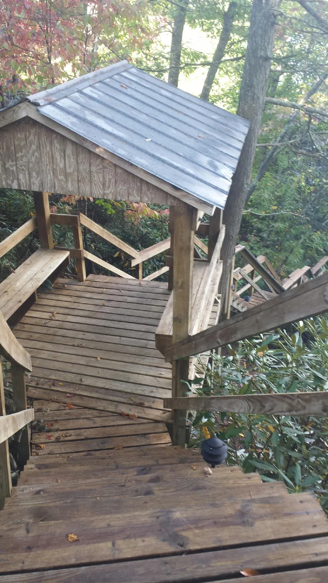 Metal roofed shelter over wooden steps on a wooded walkway — Skylight Repair & Installation work by our crew in Moyie Springs