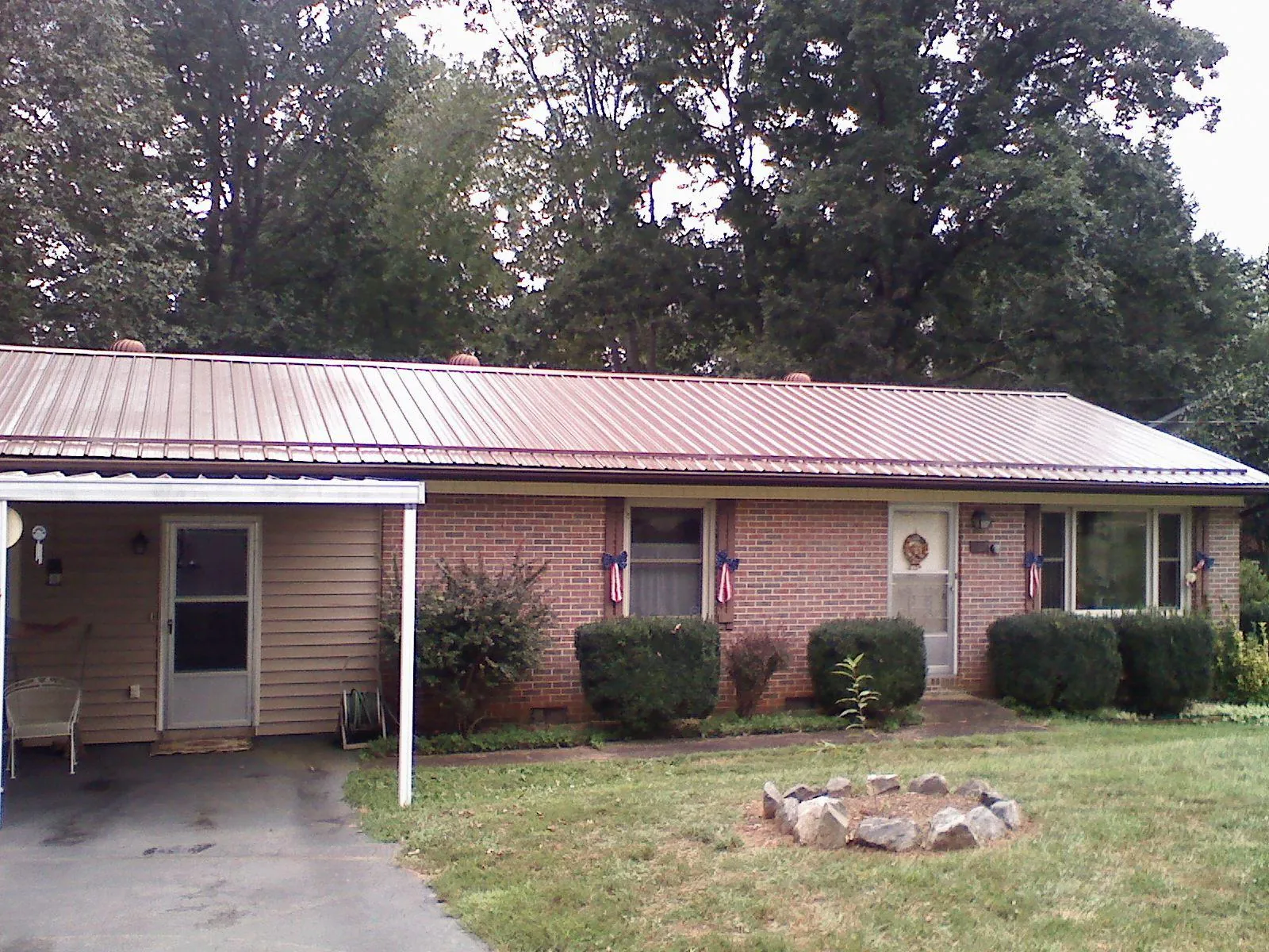 Bronze metal roof and carport on a brick ranch home — Roof Repair work by our crew in Moyie Springs