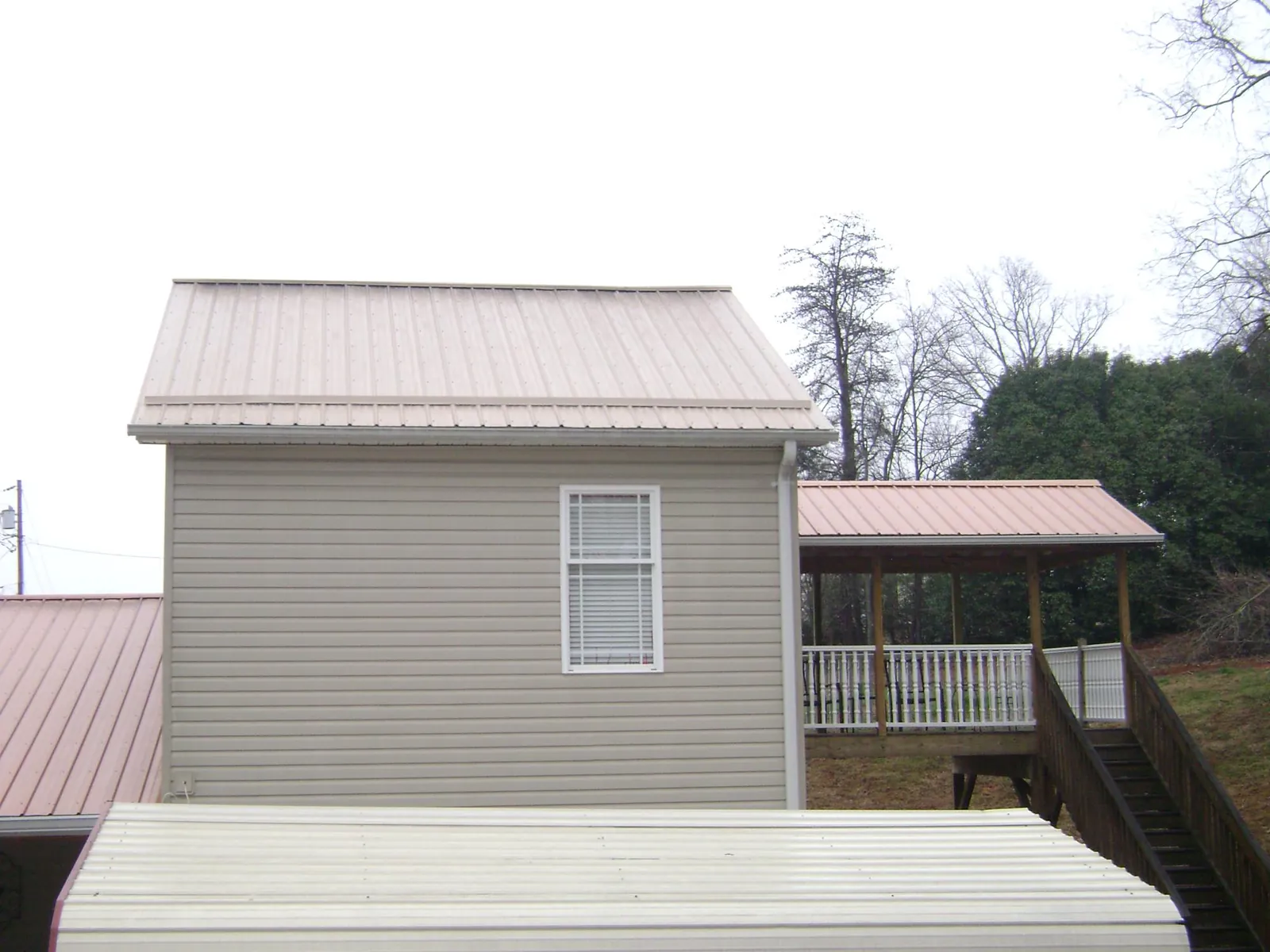 Tan metal roofs on a two story addition and attached porch, from a Roof Replacement job in Moyie Springs