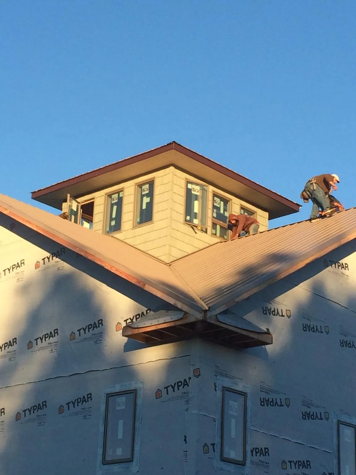 Roofers working around a rooftop cupola on a new metal roof at sunset — Roof Waterproofing in Moyie Springs by Roofing Brothers